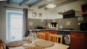 A kitchen with a dining table, chairs, a stove, oven, and a microwave. - Cosy house in Volvic - Calm, nature & volcanoes (Volvic)