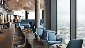 Un espace bar moderne, doté de sièges et offrant une vue sur la ville.