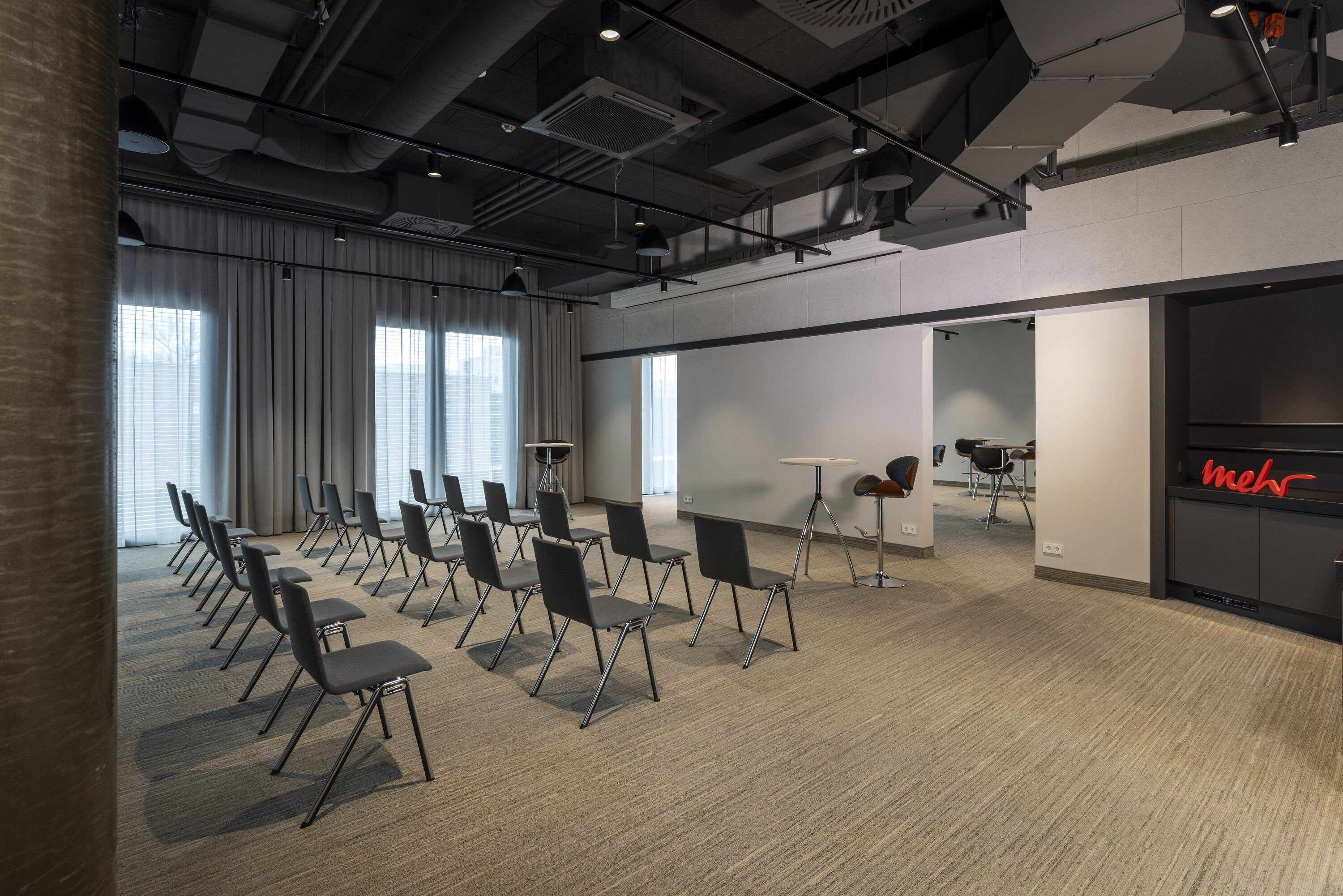 Un salón de conferencias con filas de sillas, una pizarra y un letrero de neón con un aspecto mediocre.