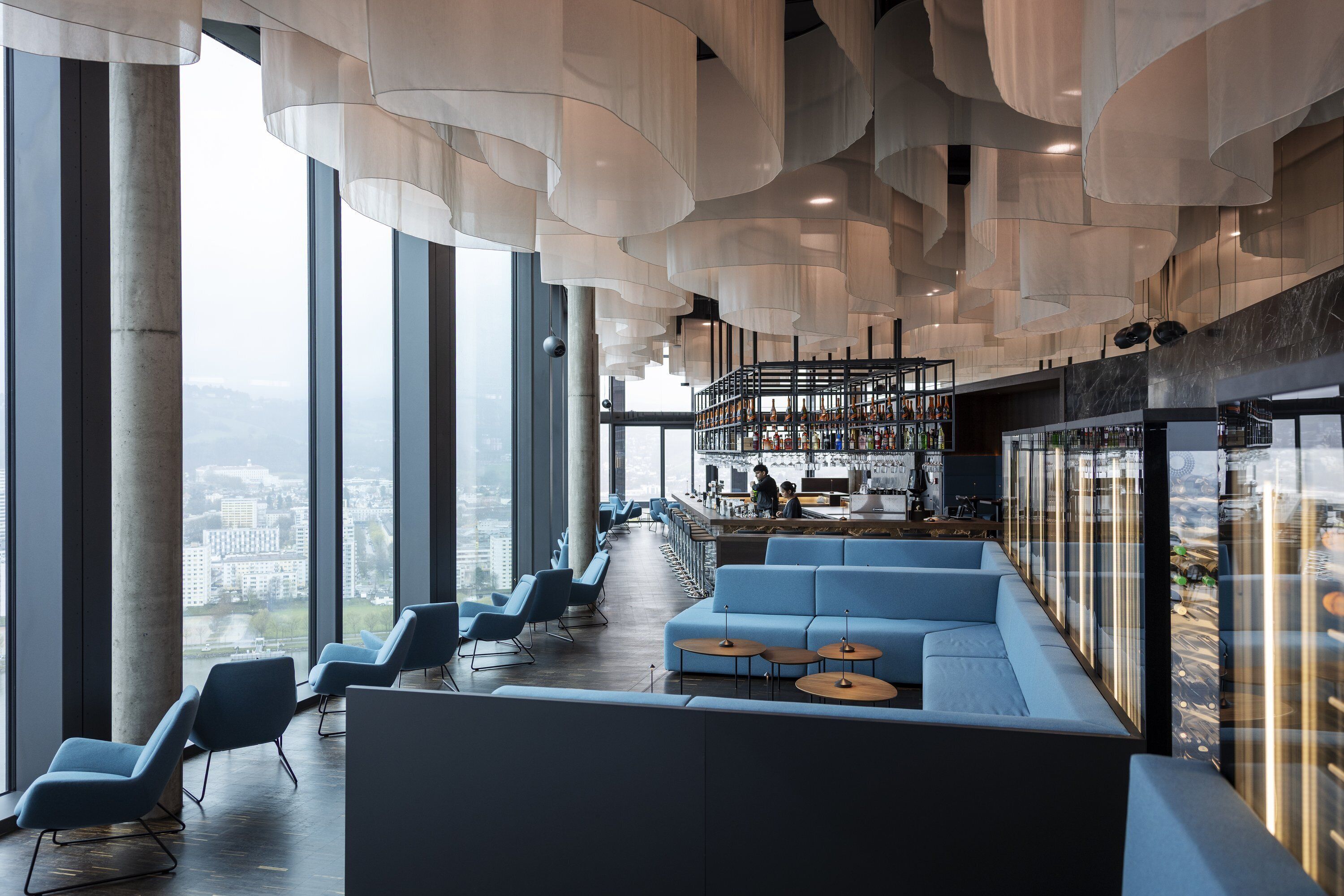 Un interno moderno con posti a sedere, un'area bar e ampie finestre con vista sulla città.