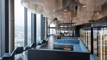 Un interno moderno con posti a sedere, un'area bar e ampie finestre con vista sulla città.