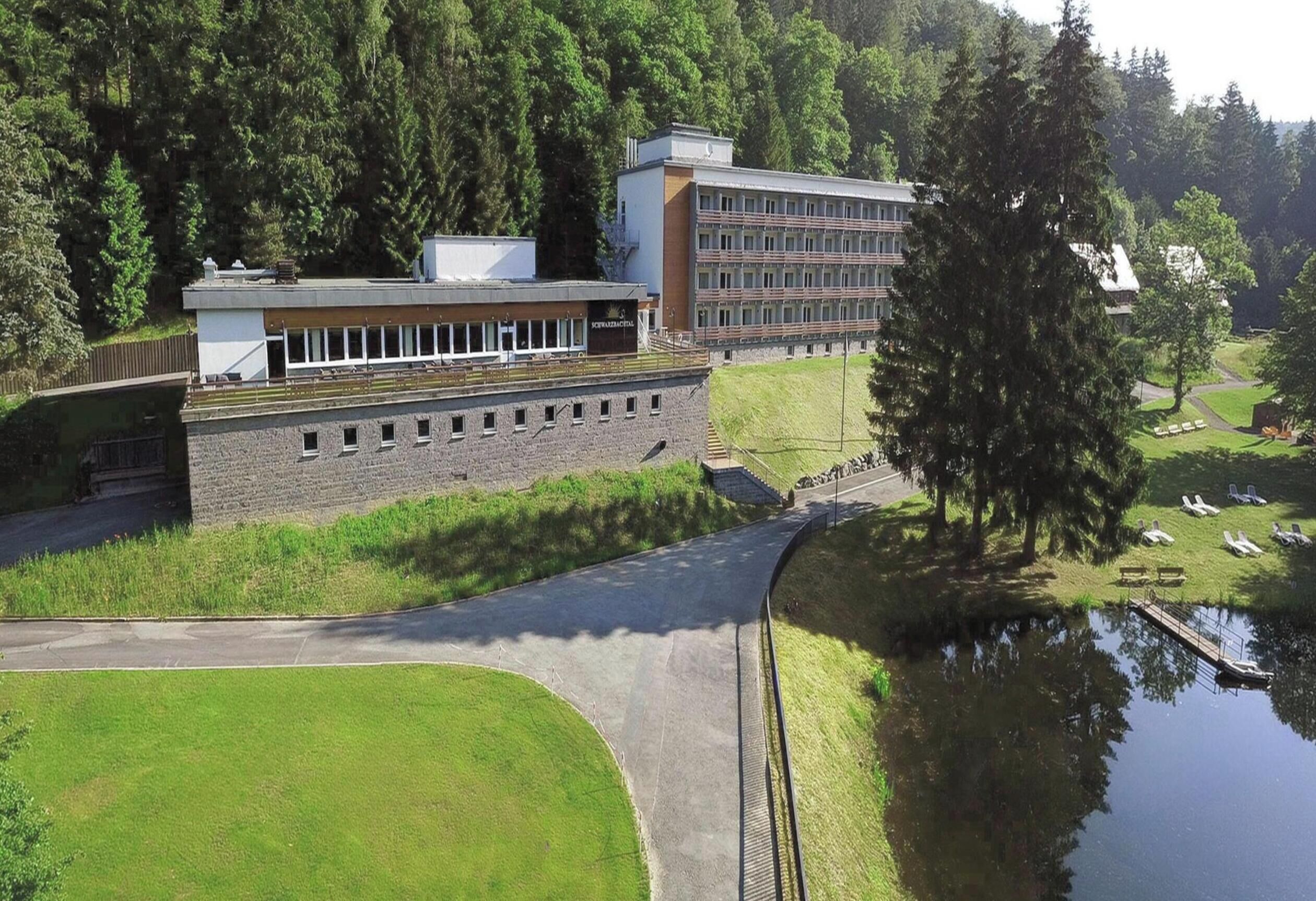 A modern building with a flat roof, a large windowed section, and a grassy area with a pond.