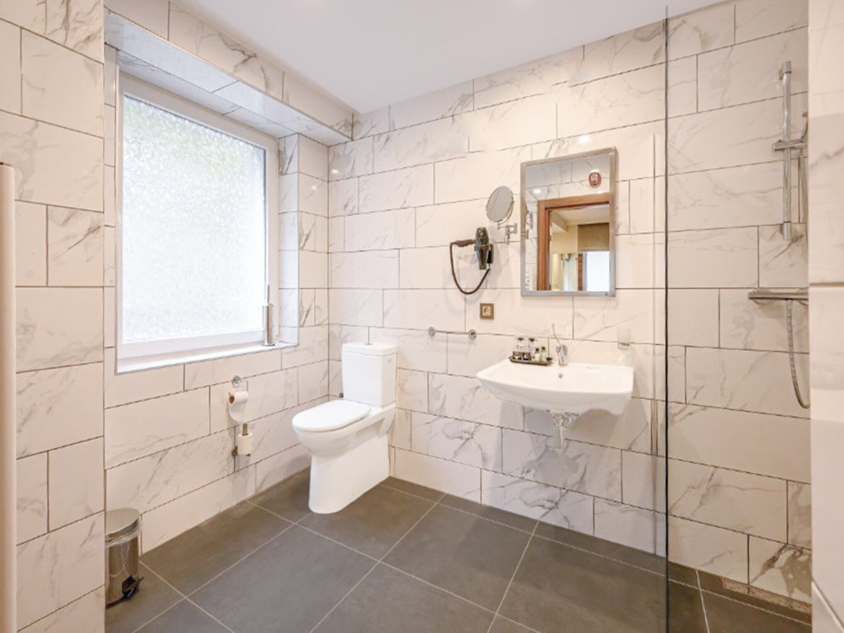 A bathroom with a toilet, sink, and shower.