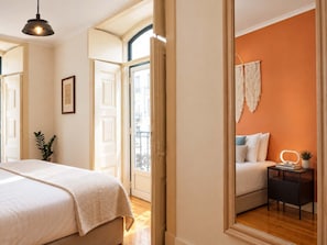 A bedroom with a bed, bedside table, and a mirror. - Sao Bento Tramview Residence (Lisboa)