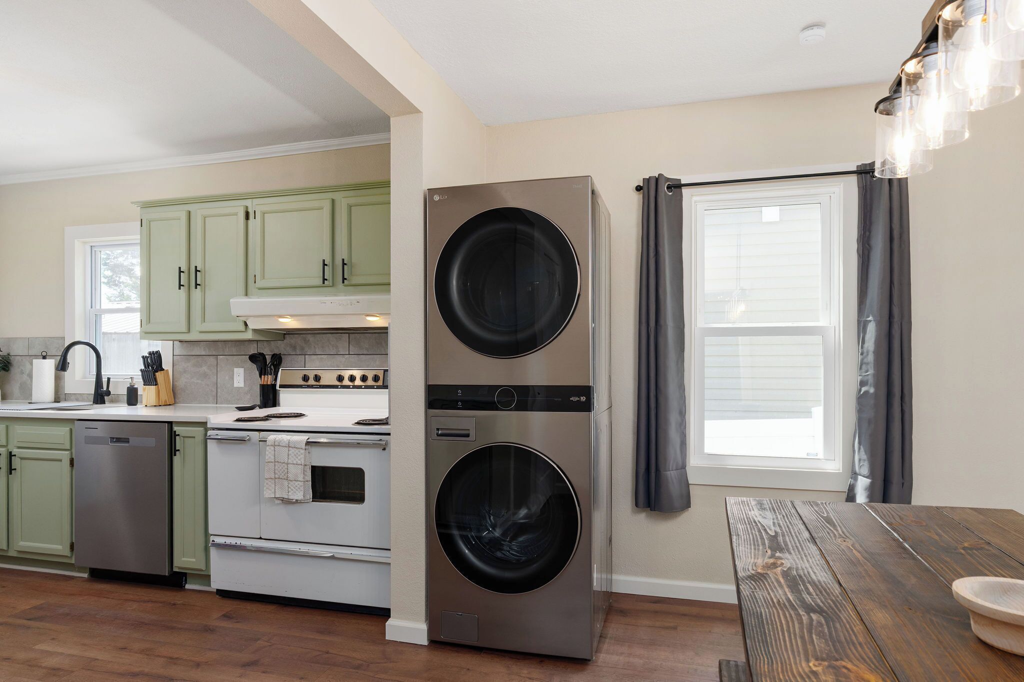A compact kitchen with a dishwasher, oven, and stacked washer-dryer unit.