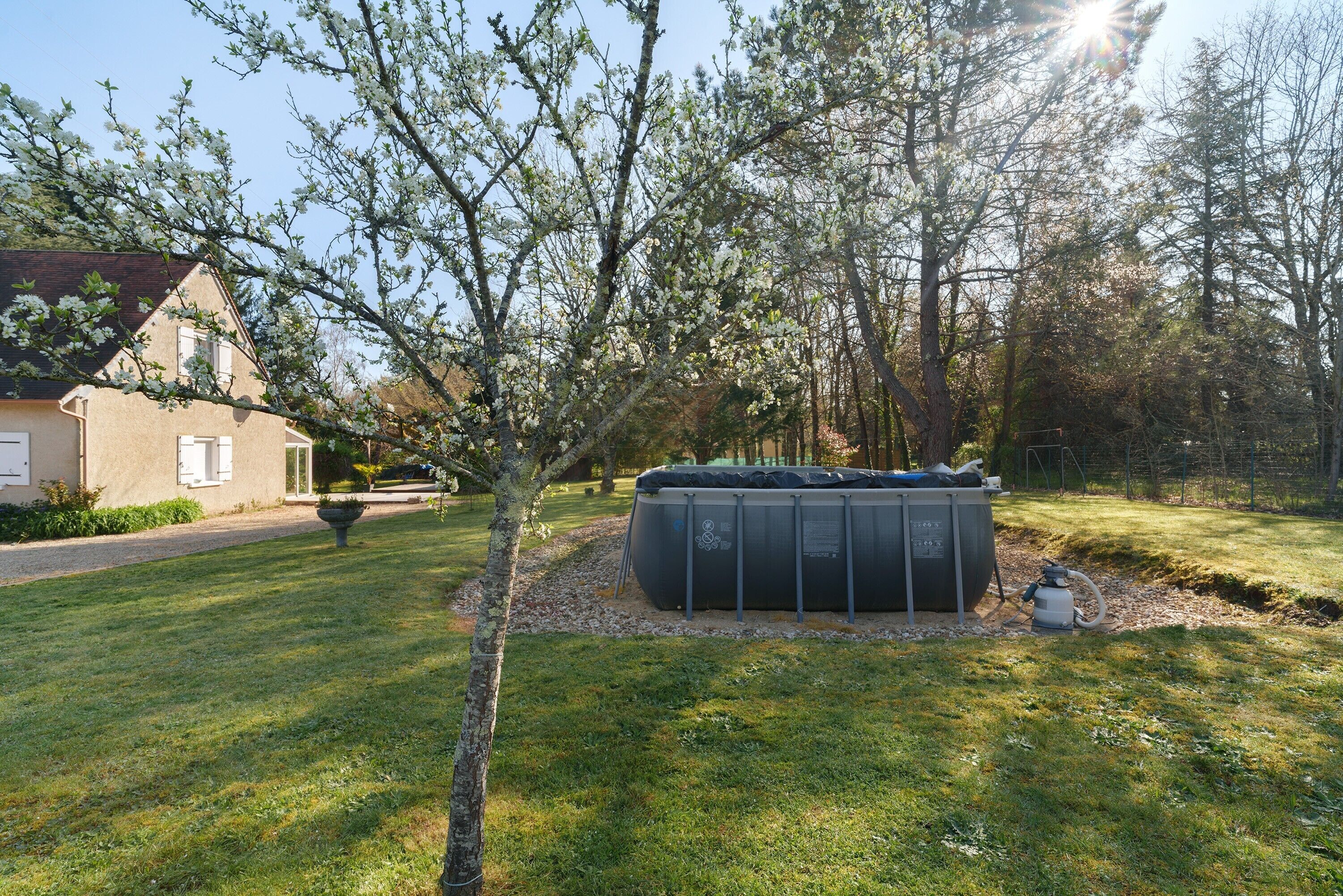 Een achtertuin met een hottub, een huis en een boom.