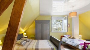Un dormitorio con cama, ventana, armario y mesita de noche.