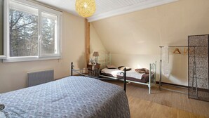Une chambre à coucher comprenant un lit, un luminaire suspendu, un radiateur, une fenêtre et une armoire.