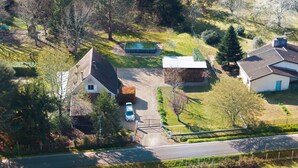 Vue aérienne d’une propriété rurale avec une maison, une piscine et une voiture garée devant.