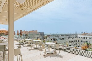 A rooftop terrace with outdoor seating and a view of the cityscape.