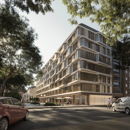 A modern multi-story building with a curved facade, large windows, and a ground-level entrance with outdoor seating.