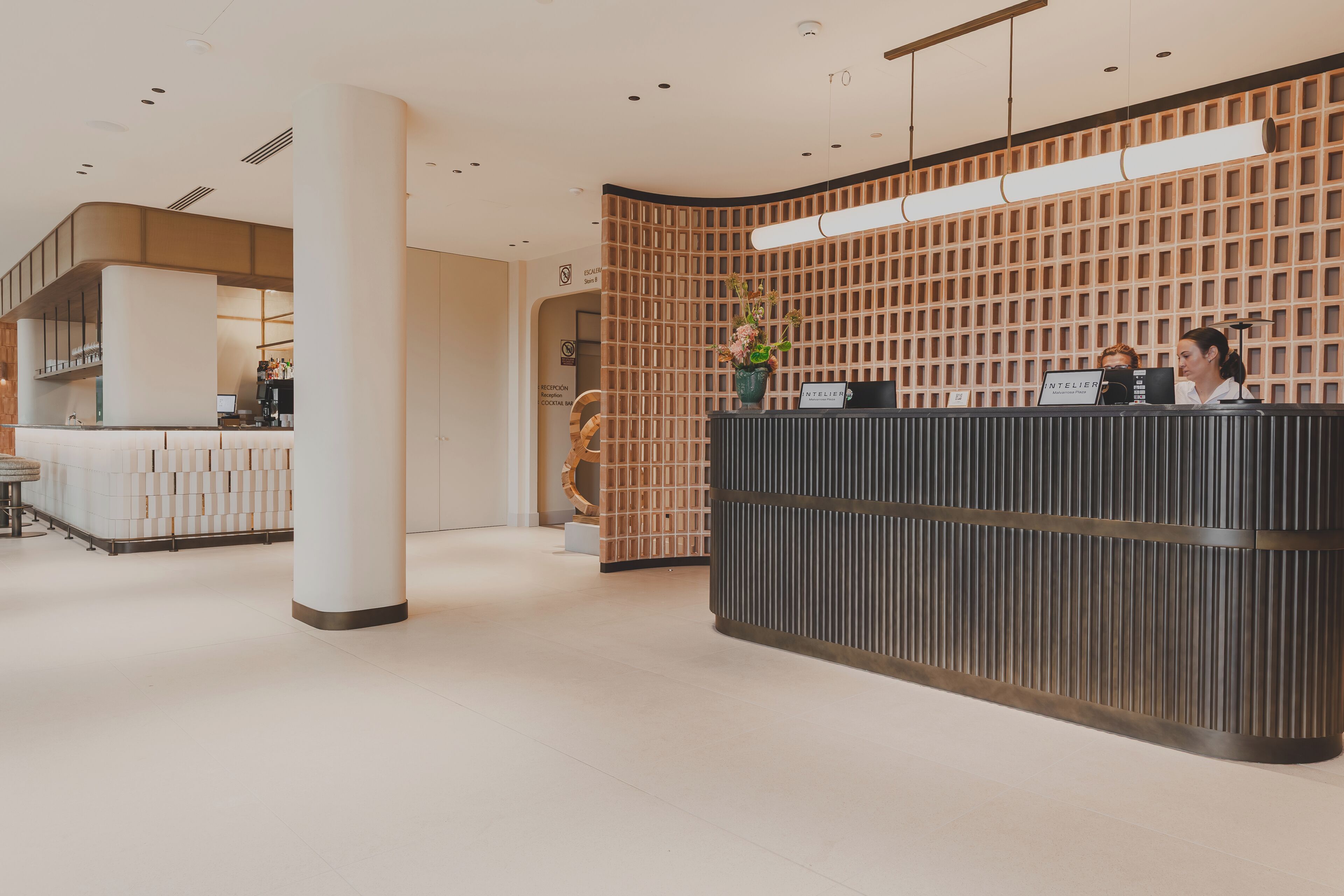 A reception desk with a modern design, a coffee bar, and a staircase leading to an upper level.