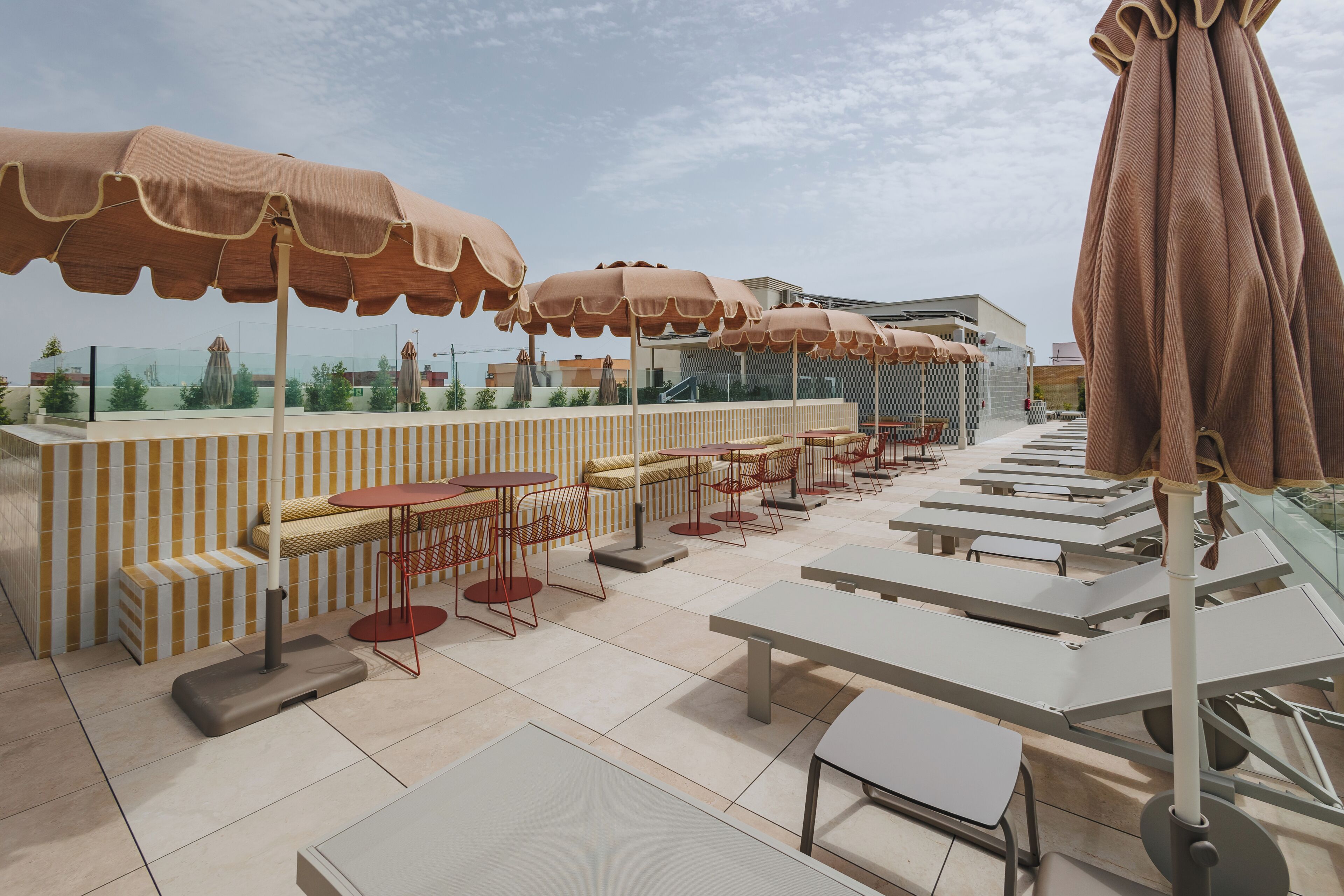 Un espace extérieur aménagé avec des tables, des chaises, des parasols et une vue sur le paysage urbain.
