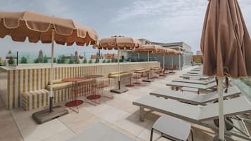Un espace extérieur aménagé avec des tables, des chaises, des parasols et une vue sur le paysage urbain.