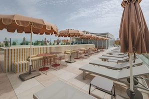 Un espacio al aire libre con mesas, sillas, sombrillas y vistas a la ciudad.
