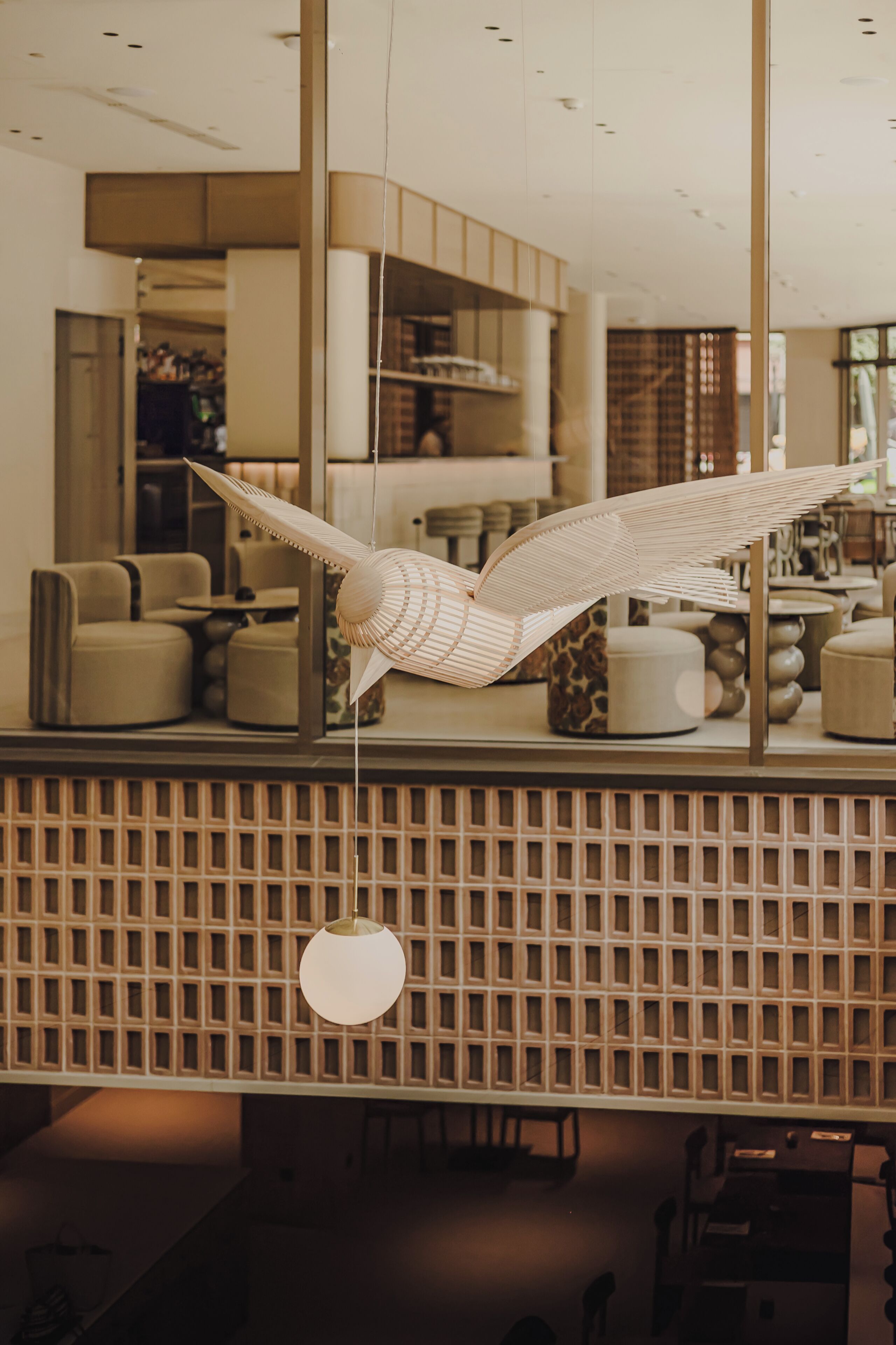 A modern interior with a hanging wooden sculpture, a patterned wall, and a round pendant light.