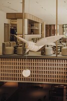 Un interior moderno con una escultura colgante de madera, un muro con diseño y una lámpara colgante redonda.