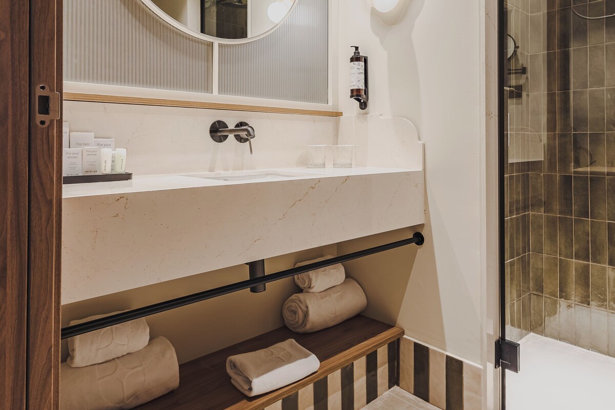 A modern bathroom with a round mirror, a sink, and a shower area.