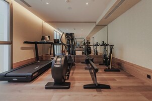 Un gimnasio con máquinas de cardio, equipo de pesas y una cinta de correr.