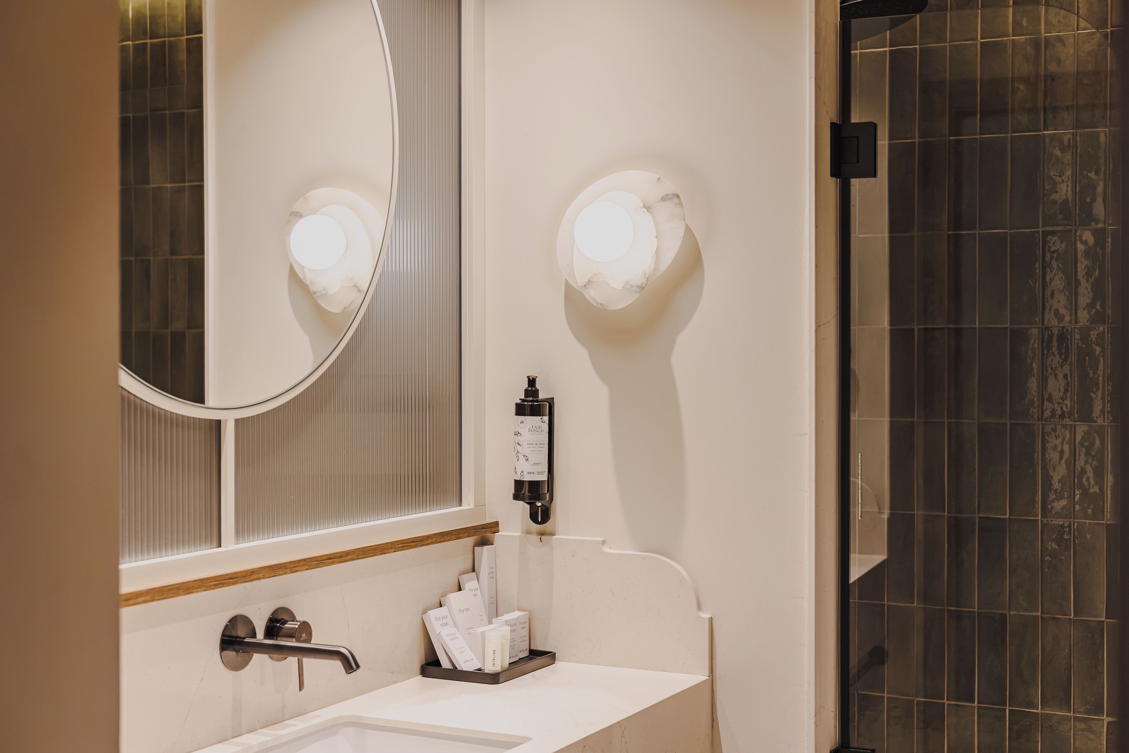 A bathroom with a white sink, a mirror, and a shower area.