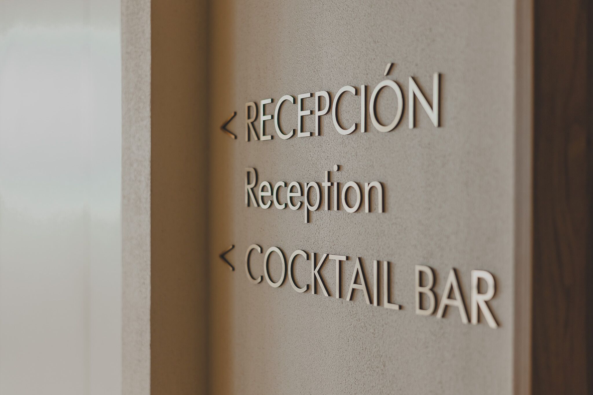 Un mur avec des panneaux indicateurs indiquant « RÉCEPTION » et « BAR À COCKTAILS », des flèches pointant vers ces lieux.