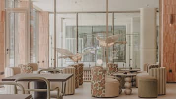 A modern interior with glass partitions, wooden panel walls, and a mix of seating options including tables and poufs.