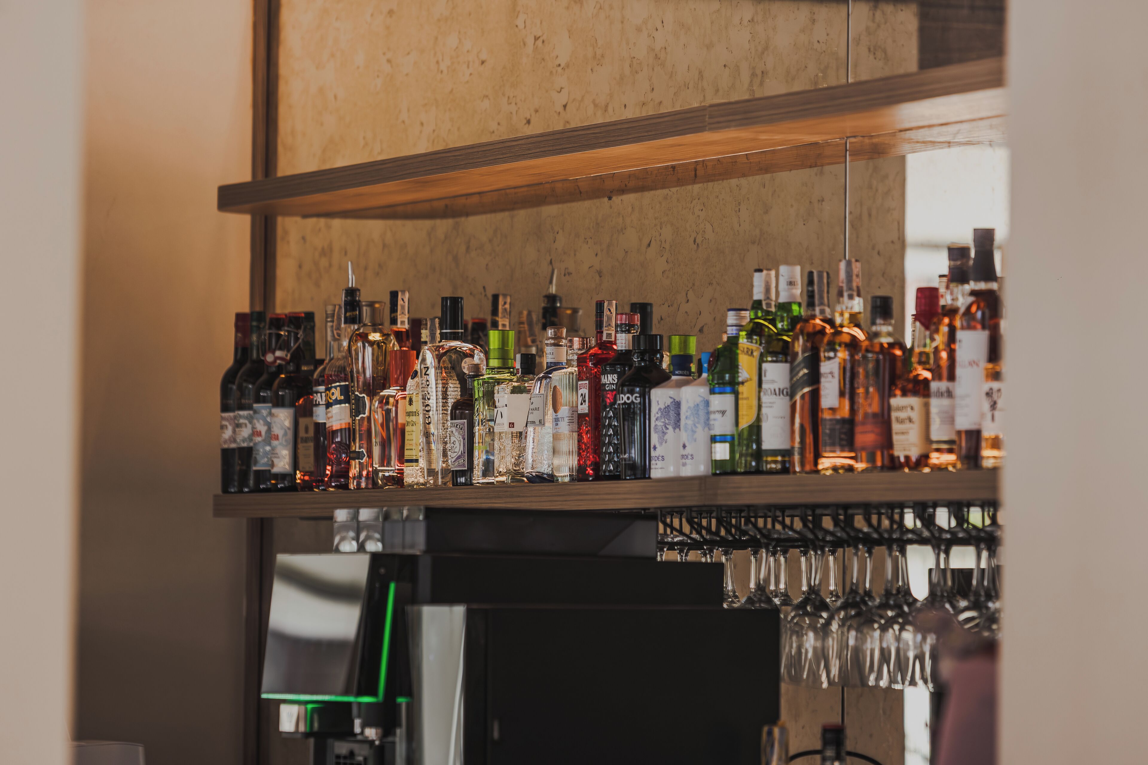 Zona de bar con diversas botellas de licores y vasos.