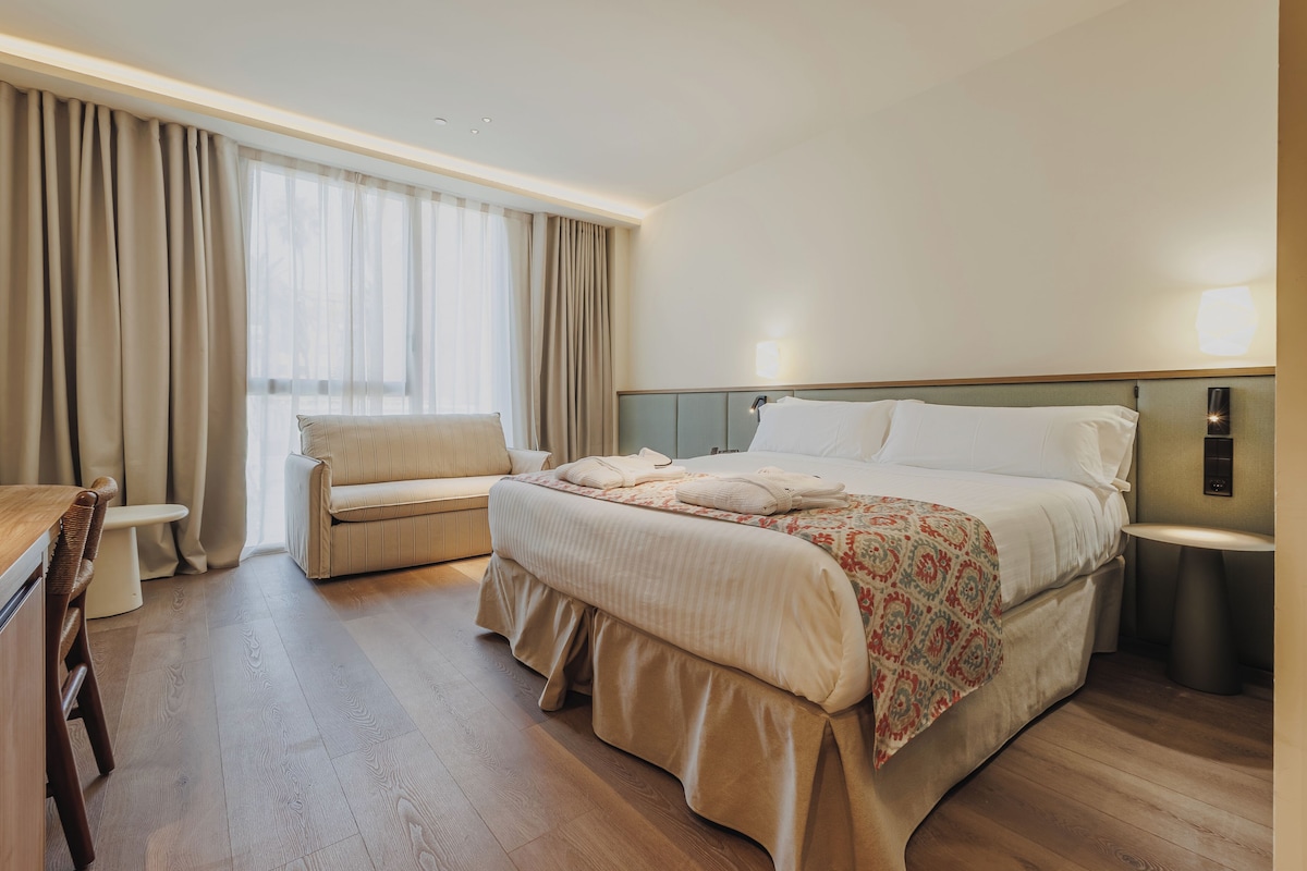 Una habitación de hotel con cama, sofá, escritorio y baño.