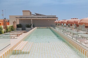 A rooftop pool with a checkered floor, surrounded by sun loungers and tables. - Malvarrosa Plaza by Intelier (Valencia)