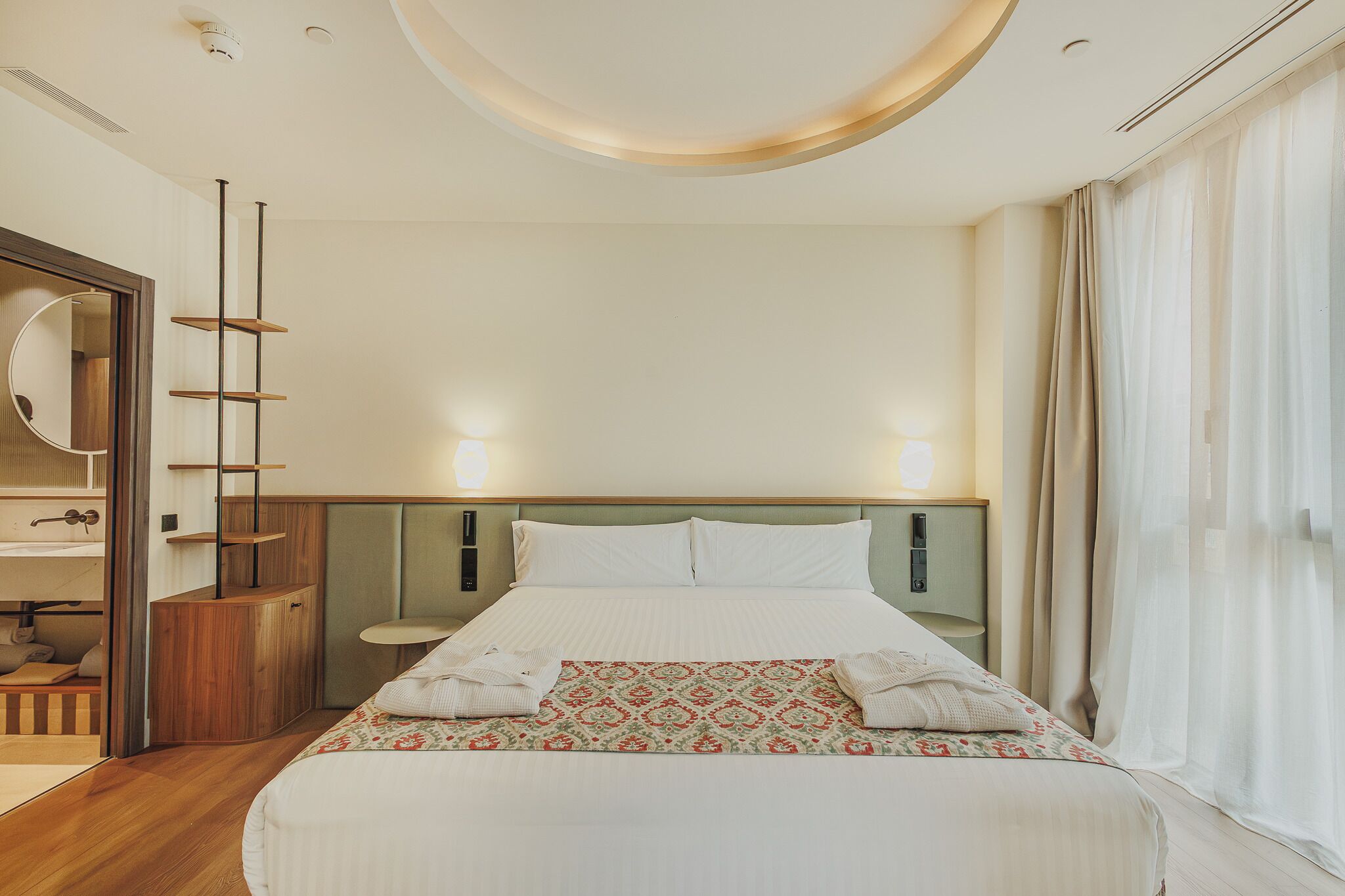 Una habitación de hotel con cama, mesitas de noche, un espejo y un armario.