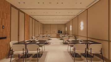 A conference room with multiple tables and chairs, wooden paneling on the walls, and recessed ceiling lighting.