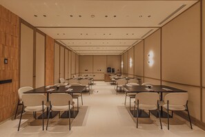 A conference room with multiple tables and chairs, wooden paneling on the walls, and recessed ceiling lighting. - Malvarrosa Plaza by Intelier (Valencia)