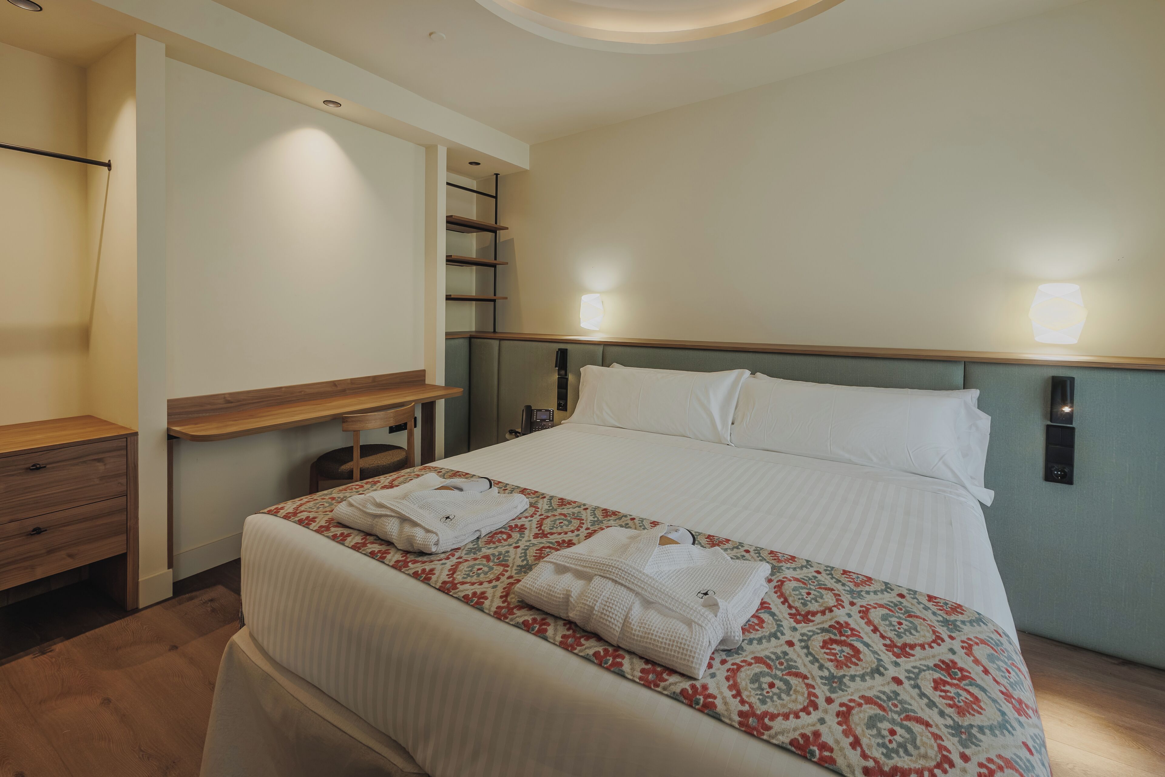 Ein Hotelzimmer mit Bett, Nachttischen, Schreibtisch und Stuhl.