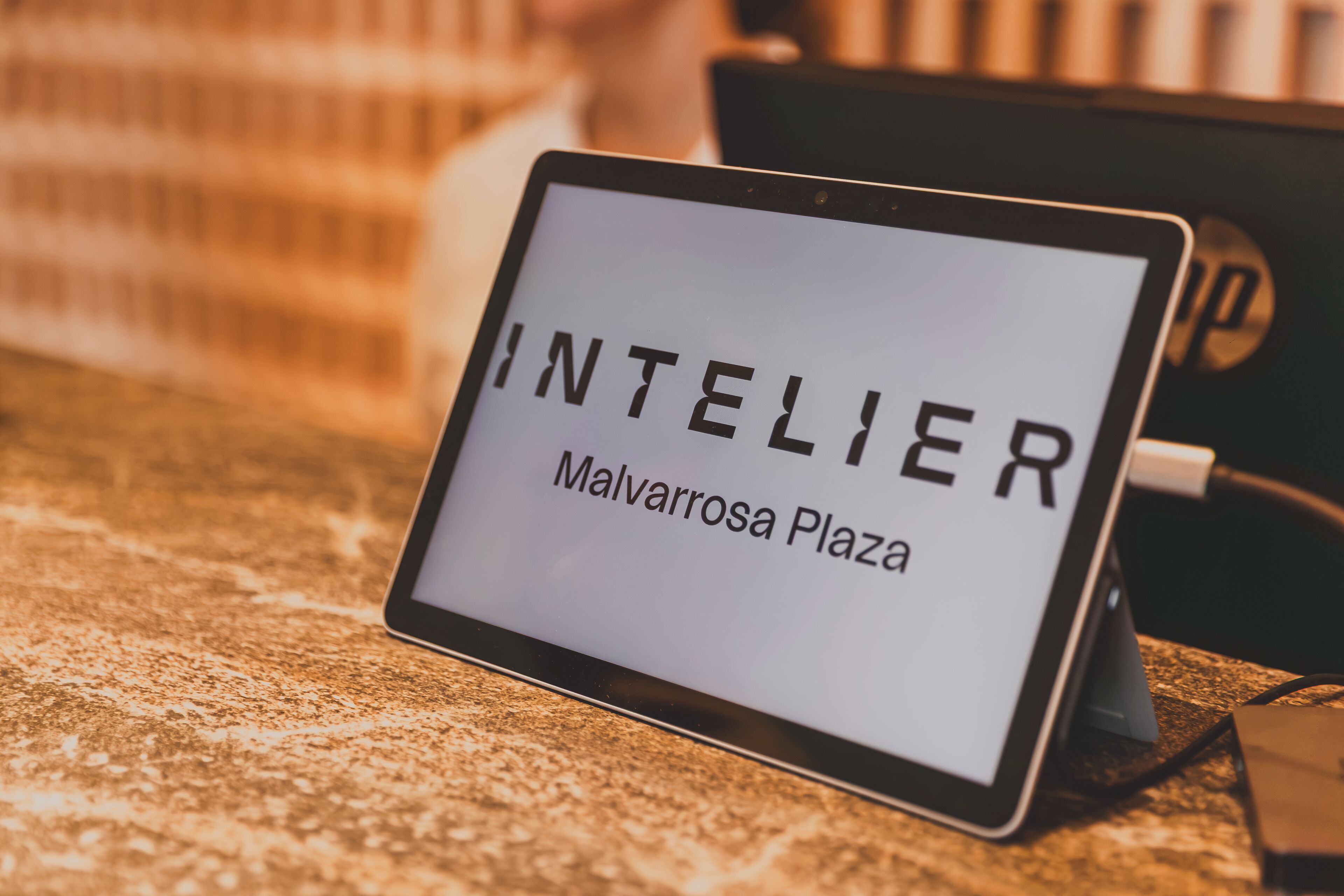 Un panneau numérique affichant la mention « INTELIER Malvarrosa Plaza » sur une tablette.