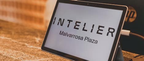 A digital sign displaying 'INTELIER Malvarrosa Plaza' on a tablet.