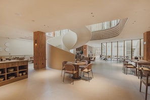 Un interior espacioso con una escalera espiral central, varios rincones de estar y una cocina visible al fondo.