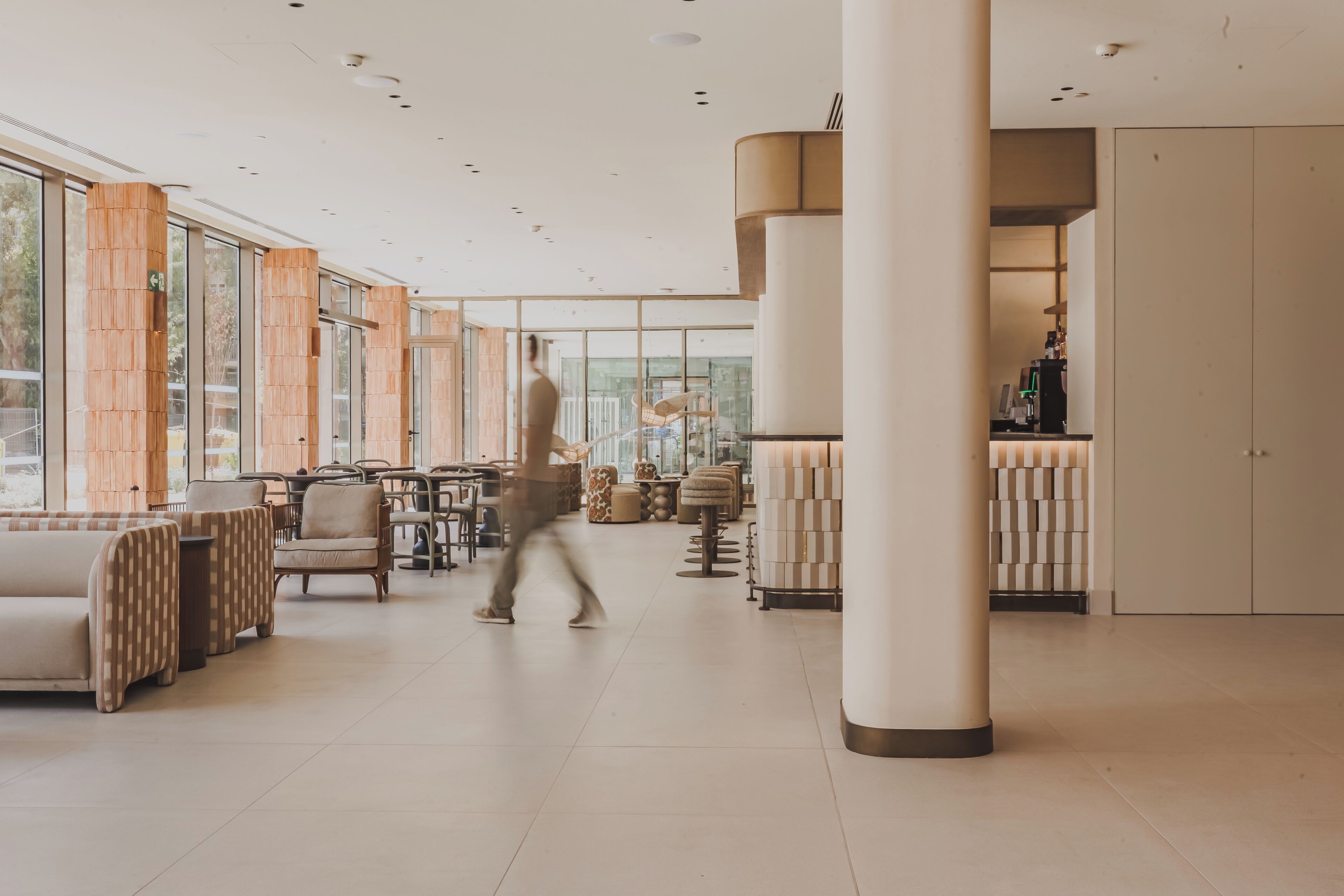 Un intérieur spacieux comprenant un bar, des espaces de détente et de grandes fenêtres.