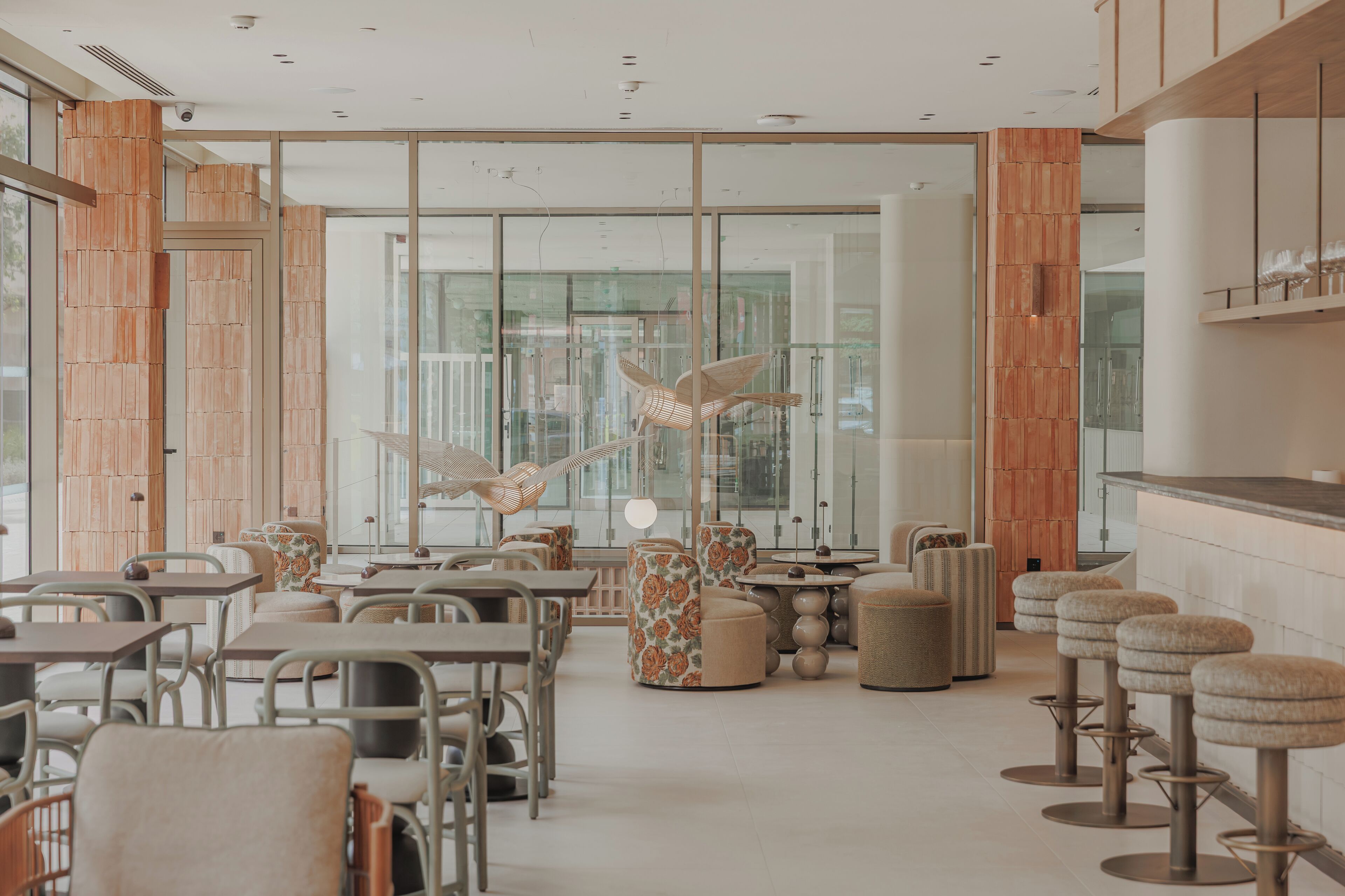 Un intérieur moderne agrémenté d’éléments en bois, de cloisons en verre et d’une variété de sièges, notamment des tables et des chaises.