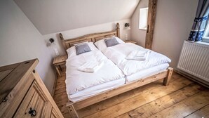 Una cama de madera en una habitación con techo inclinado y un radiador.