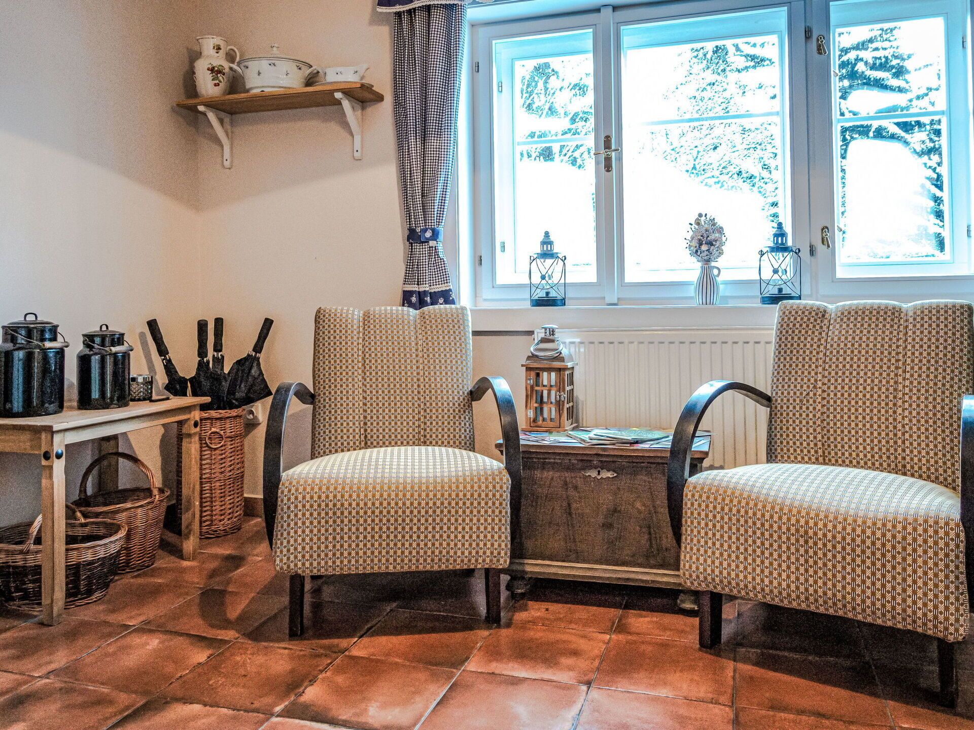 A cozy room with two patterned chairs, a wooden table, and a window with a view of trees.