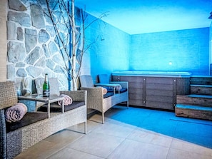 Ein gemütlicher Loungebereich mit Korbmöbeln, einer Steinwand und einem blau gefliesten Boden.