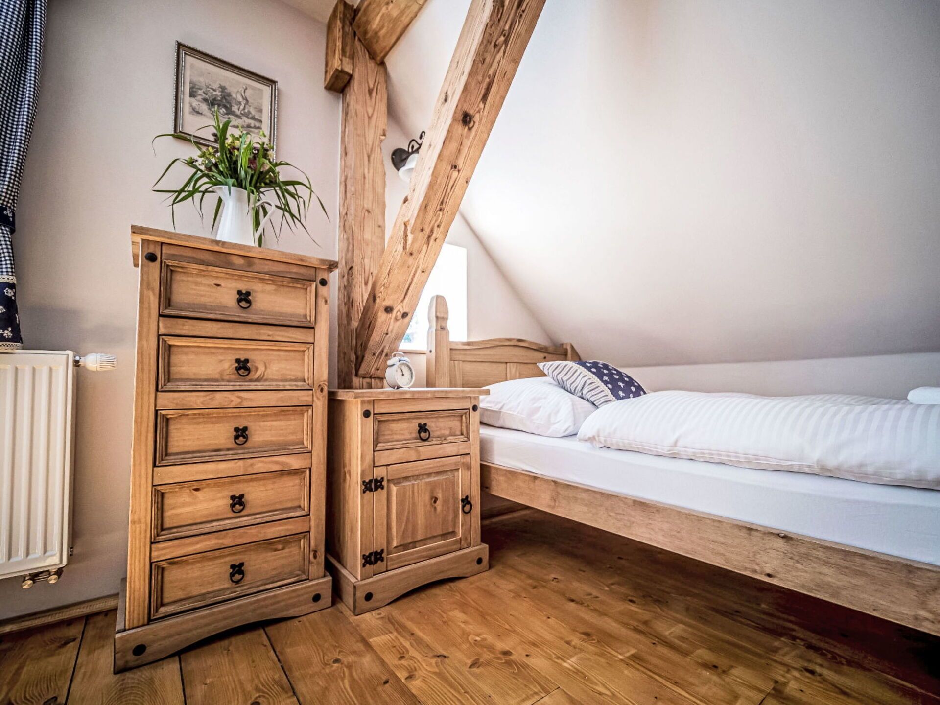 A bedroom with a wooden bed, a nightstand, and a dresser with drawers.