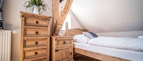 A bedroom with a wooden bed, a nightstand, and a dresser with drawers.