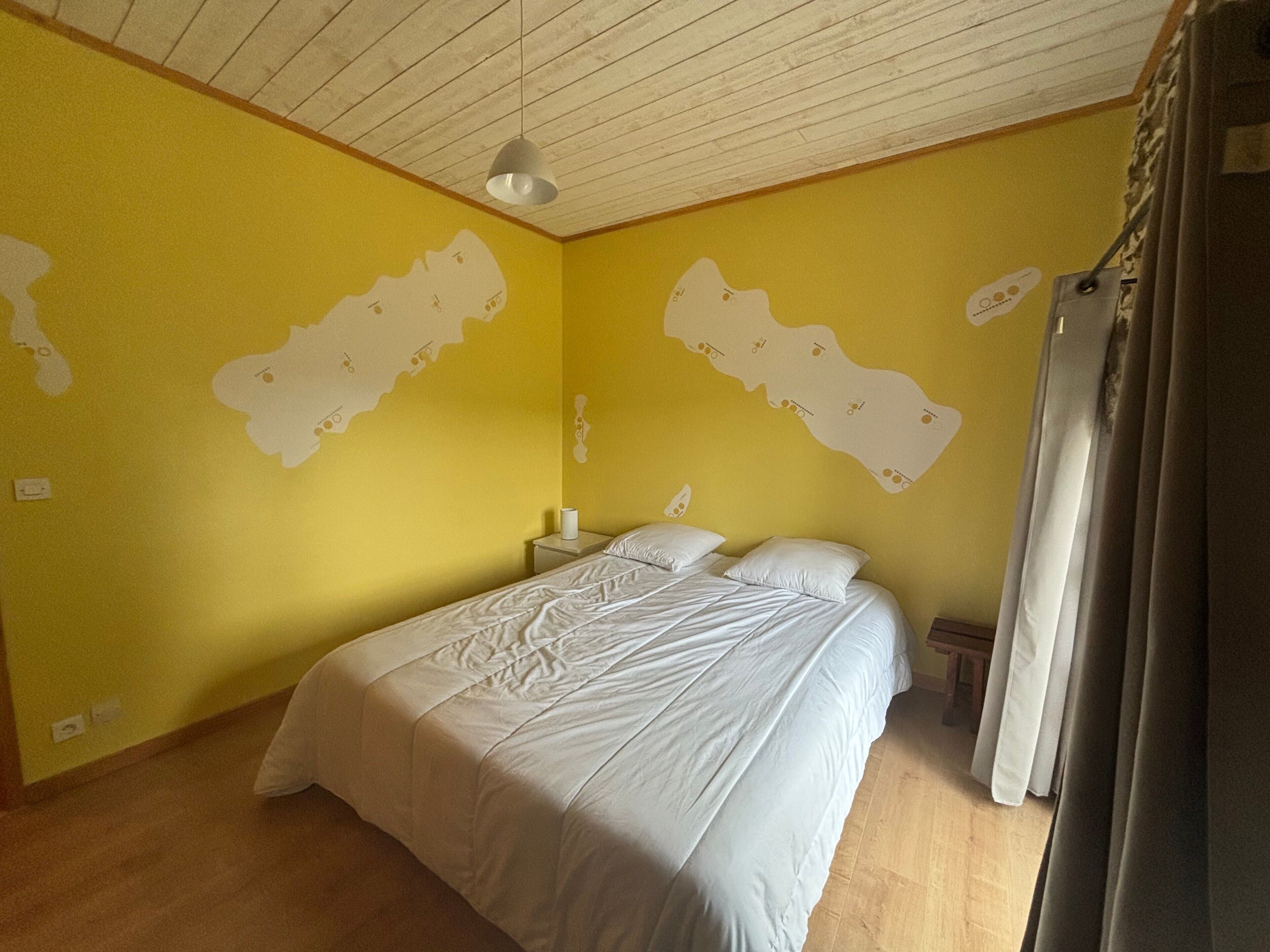 A bedroom with a bed, a nightstand, a lamp, and a map on the wall.