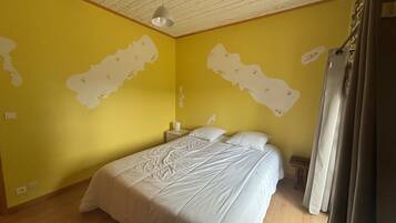 A bedroom with a bed, a nightstand, a lamp, and a map on the wall.