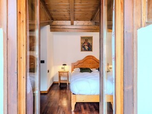 Ein Zimmer mit Holzrahmen, ausgestattet mit einem Bett, einem Nachttisch, einer Lampe und einem Bild an der Wand.