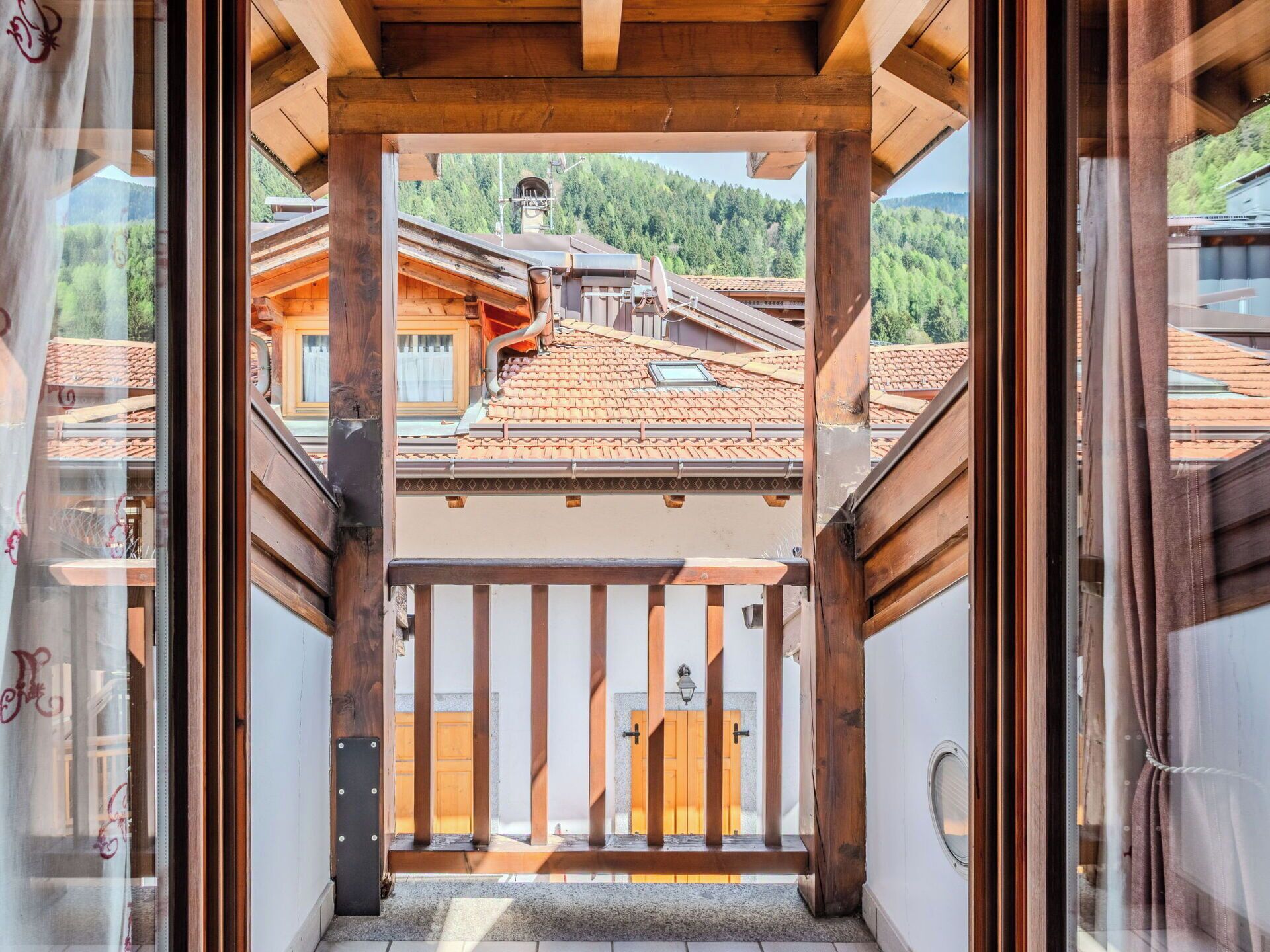 A wooden balcony with a view of traditional buildings and a mountain in the background.