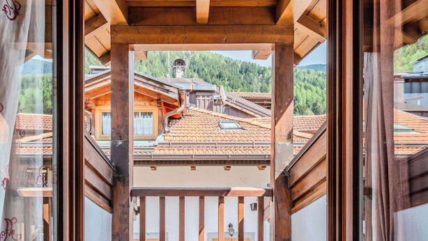 Ein Holzbalkon mit Blick auf traditionelle Gebäude und einen Berg im Hintergrund.