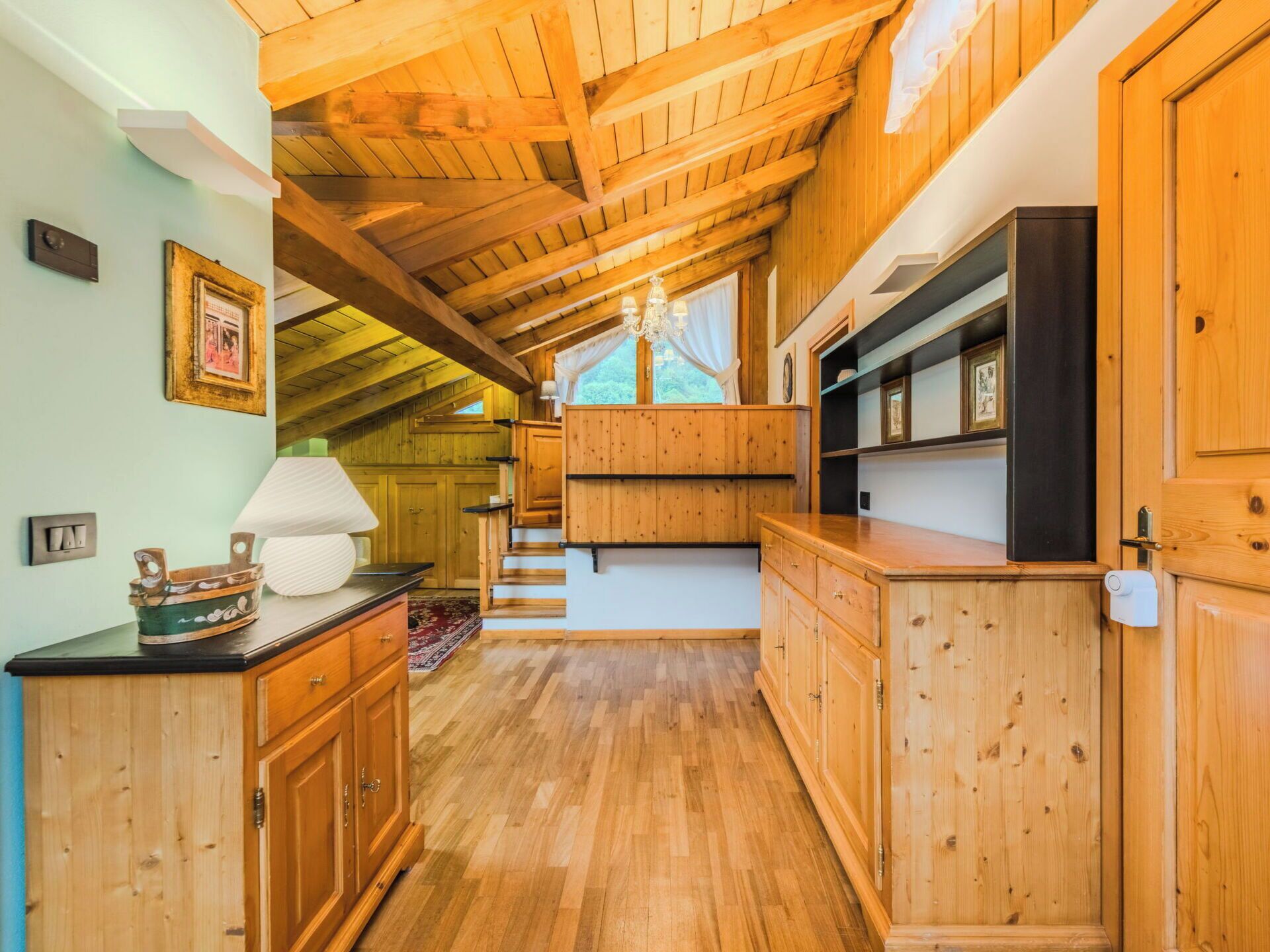 Un intérieur en bois avec un escalier, des meubles en bois et un lustre.