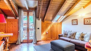 Ein Holzinnenraum mit einer Couch, einem Hocker und einem Tisch mit einer roten Lampe.